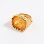 Gold ring with a cherub design on a white background