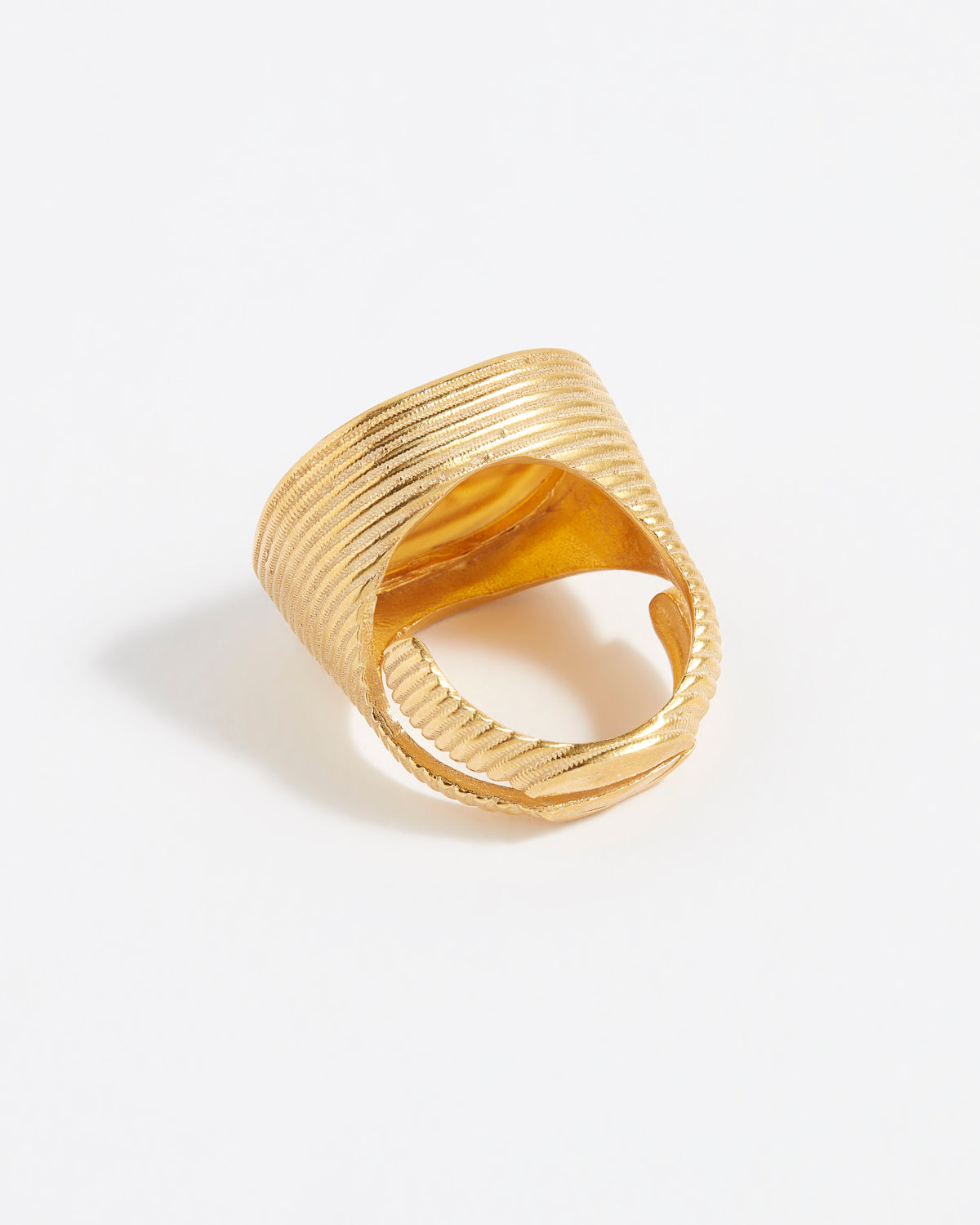 Gold ring with textured design on a white background