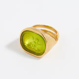 Gold ring with a green stone on a white background