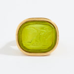 Green stone ring with gold setting on a white background