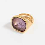 Gold ring with a purple stone on a white background