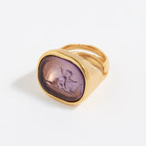 Gold ring with a purple stone on a white background