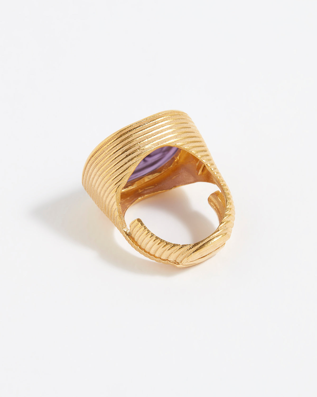 Gold ring with a purple stone on a white background