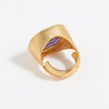 Gold ring with a purple stone on a white background