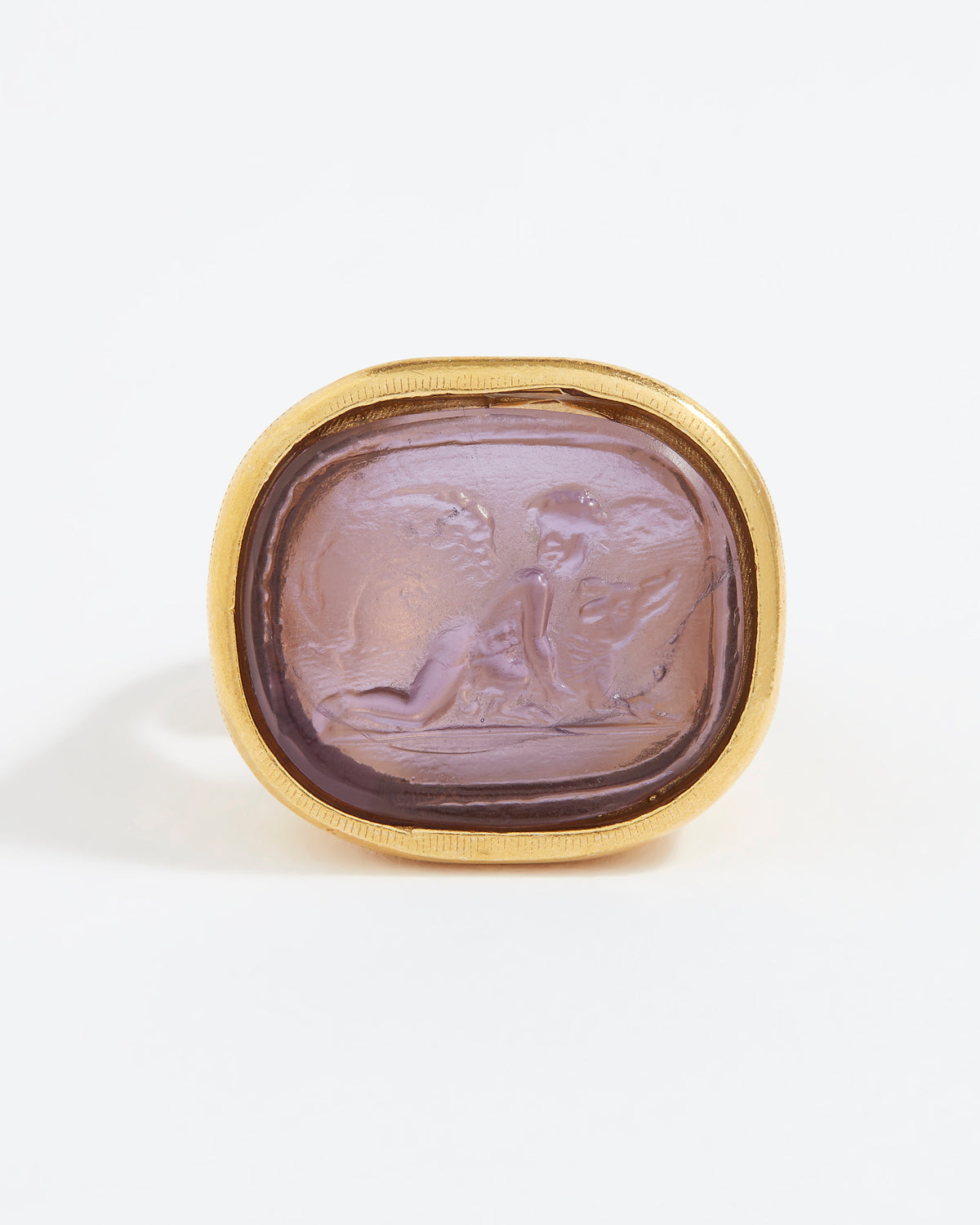 Gold ring with a purple stone featuring an engraved design on a white background