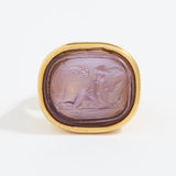 Gold ring with a purple stone featuring an engraved design on a white background