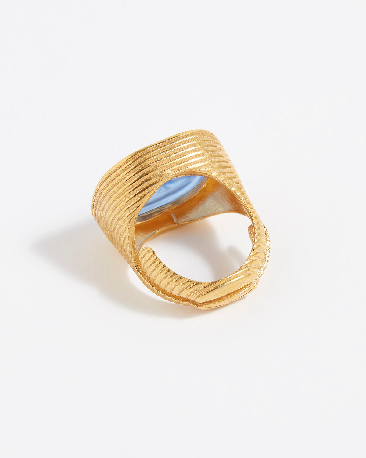 Gold textured ring with a blue stone on a light gray background