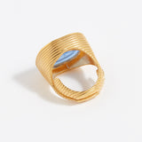 Gold textured ring with a blue stone on a light gray background