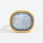 Gold ring with a stone featuring an engraved design on a white background