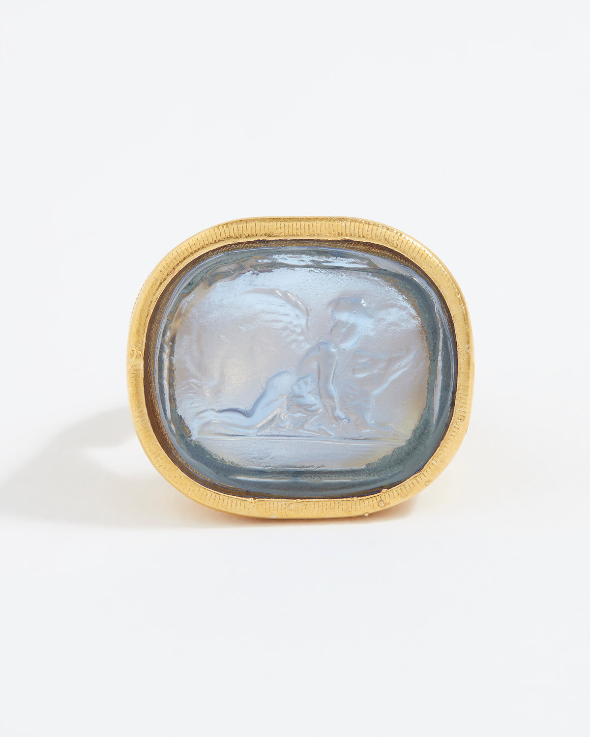 Gold ring with a stone featuring an engraved design on a white background