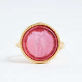 Gold ring with a pink stone on a white background