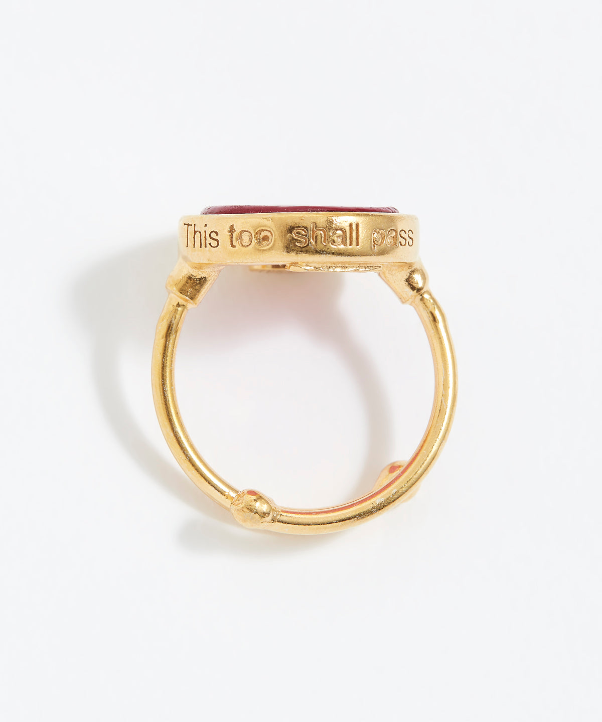 Gold ring with engraved text "This Too Shall Pass" on a white background
