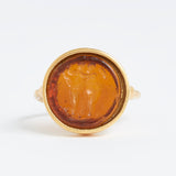 Gold ring with a circular topaz stone featuring a engraved design on a white background