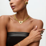 Image of a lady wearing black dress, gold chain bracelet, matching choker with round onyx detail and matching stud earrings.