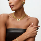 Image of a lady wearing black dress, gold chain bracelet, matching choker with round onyx detail and matching stud earrings.