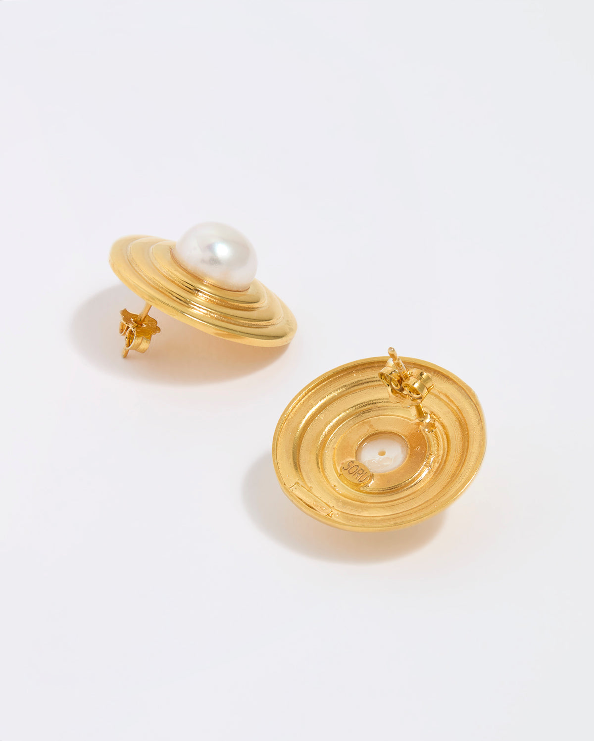 Gold earrings with pearl centers on a white background, showing back of earring