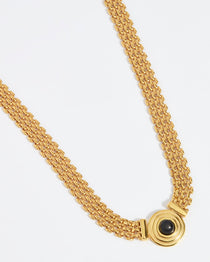 Product shot of gold plated linked necklace with central onyx disc stone on a white background.