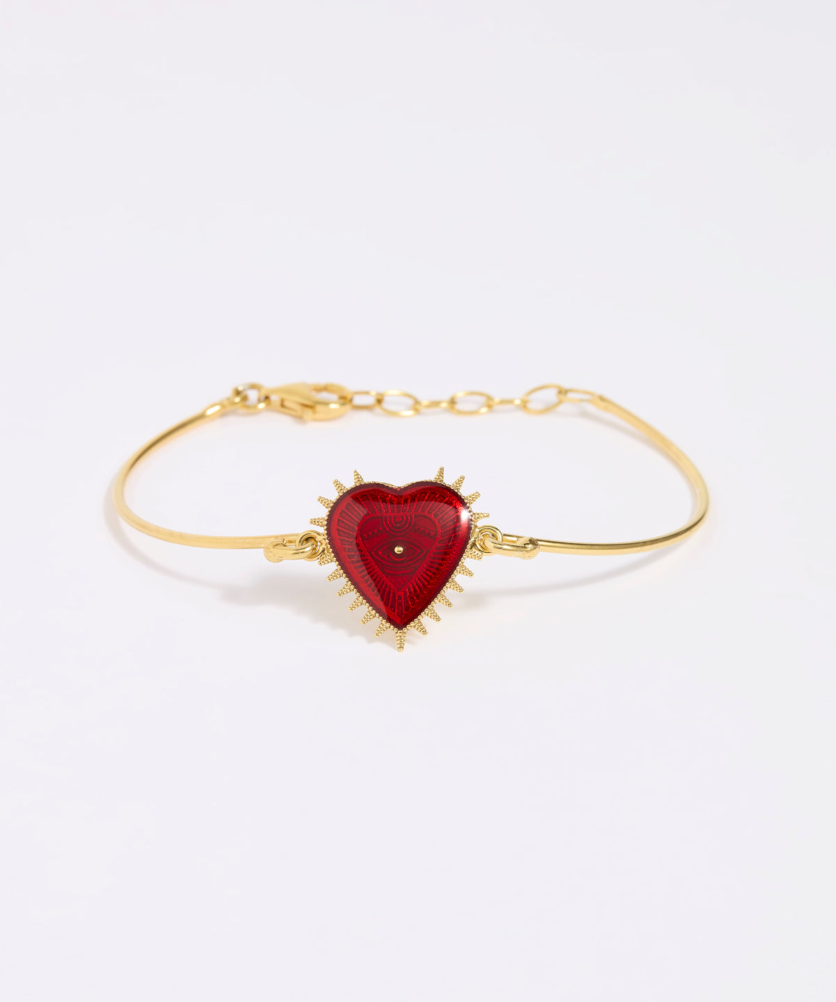 Gold bracelet with a red heart-shaped charm on a white background