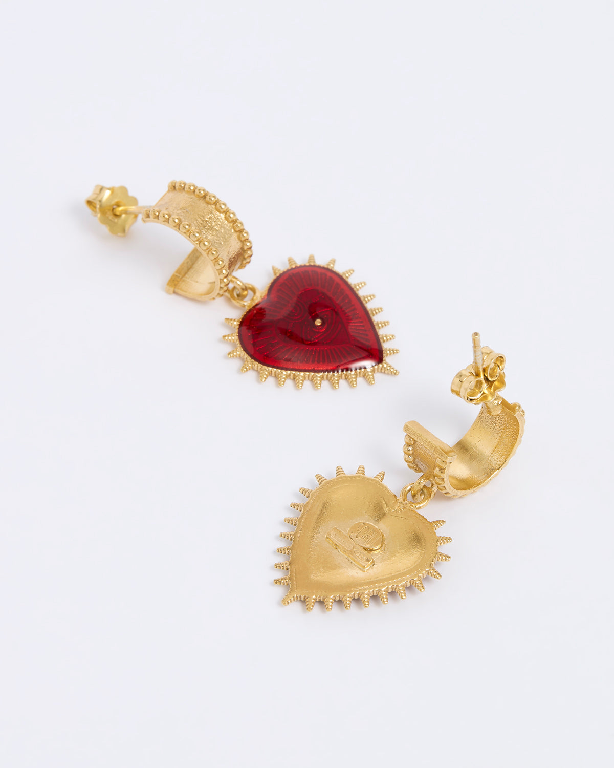 Gold heart-shaped earrings with a red gemstone on a white background