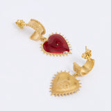 Gold heart-shaped earrings with a red gemstone on a white background