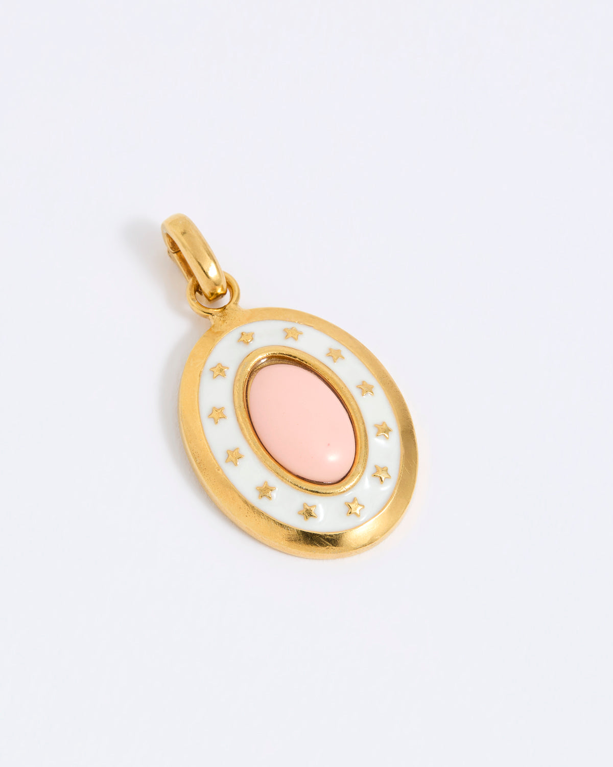 Oval gold coloured pendant with a pink center on a light grey background