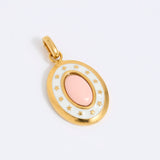 Oval gold coloured pendant with a pink center on a light grey background