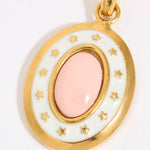 Gold coloured pendant with a pink central stone and star accents on a white background