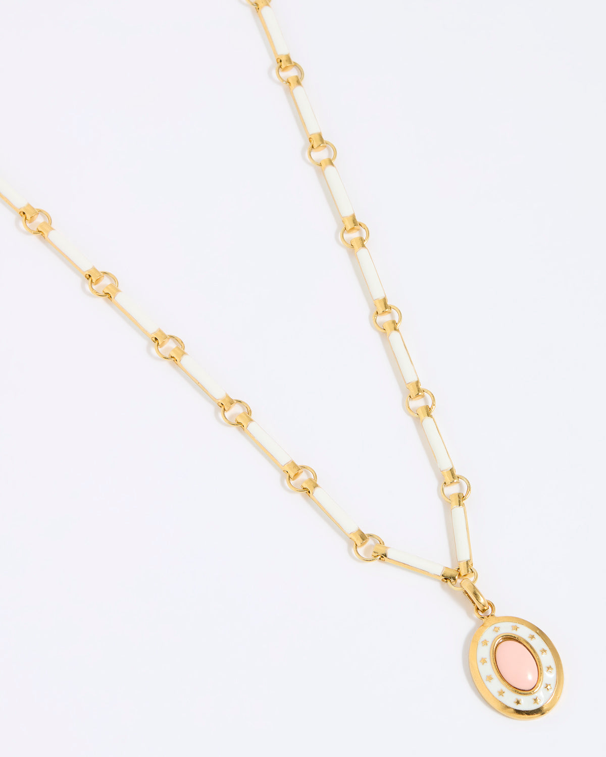 Gold coloured and white enamel necklace with a pink pendant on a white background