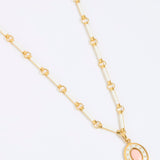 Gold coloured and white enamel necklace with a pink pendant on a white background