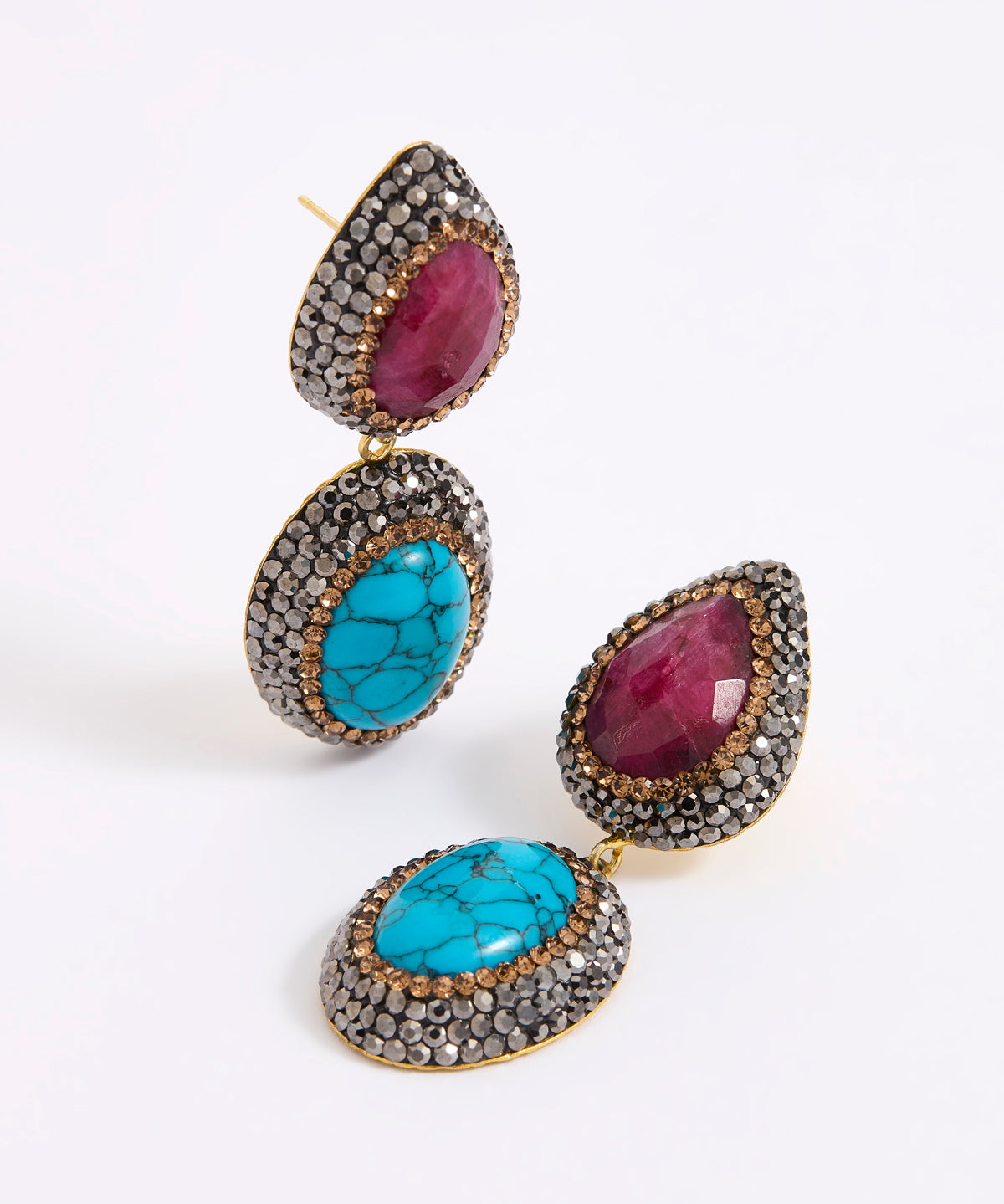 A pair of gold-tone drop earrings featuring oval turquoise and teardrop ruby gemstones, surrounded by a dark silver crystal setting.