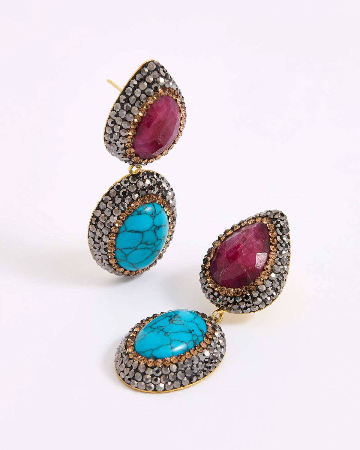 A pair of gold-tone drop earrings featuring oval turquoise and teardrop ruby gemstones, surrounded by a dark silver crystal setting.