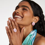 Smiling model wearing Soru Jewellery large pink stud earrings surrounded by crystals and a matching ring