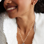 model shot wearing Soru Jewellery Crystal Embellished Silver Shell Charm on a pearl charm necklace and wearing crystal mini hoops