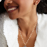 model shot wearing Soru Jewellery Crystal Embellished Silver Shell Charm on a pearl charm necklace and wearing crystal mini hoops