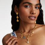 Model shot wearing soru jewellery Crystal Embellished Silver Shell Charm with other nautical charms attached to a charm chain and wearings shell drop earrings with a gold ring