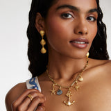 Model shot wearing soru jewellery Crystal Embellished Silver Shell Charm with other nautical charms attached to a charm chain and wearings shell drop earrings with a gold ring
