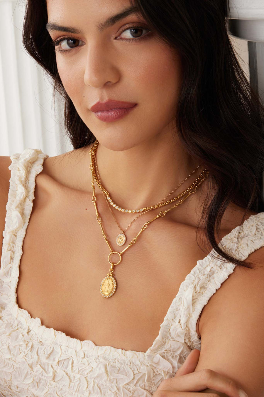 model shot of the Soru Jewellery madonna gold and crystal charm worn layered with other necklaces 