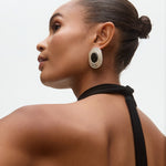Woman wearing large onyx and silver earrings with a neutral background