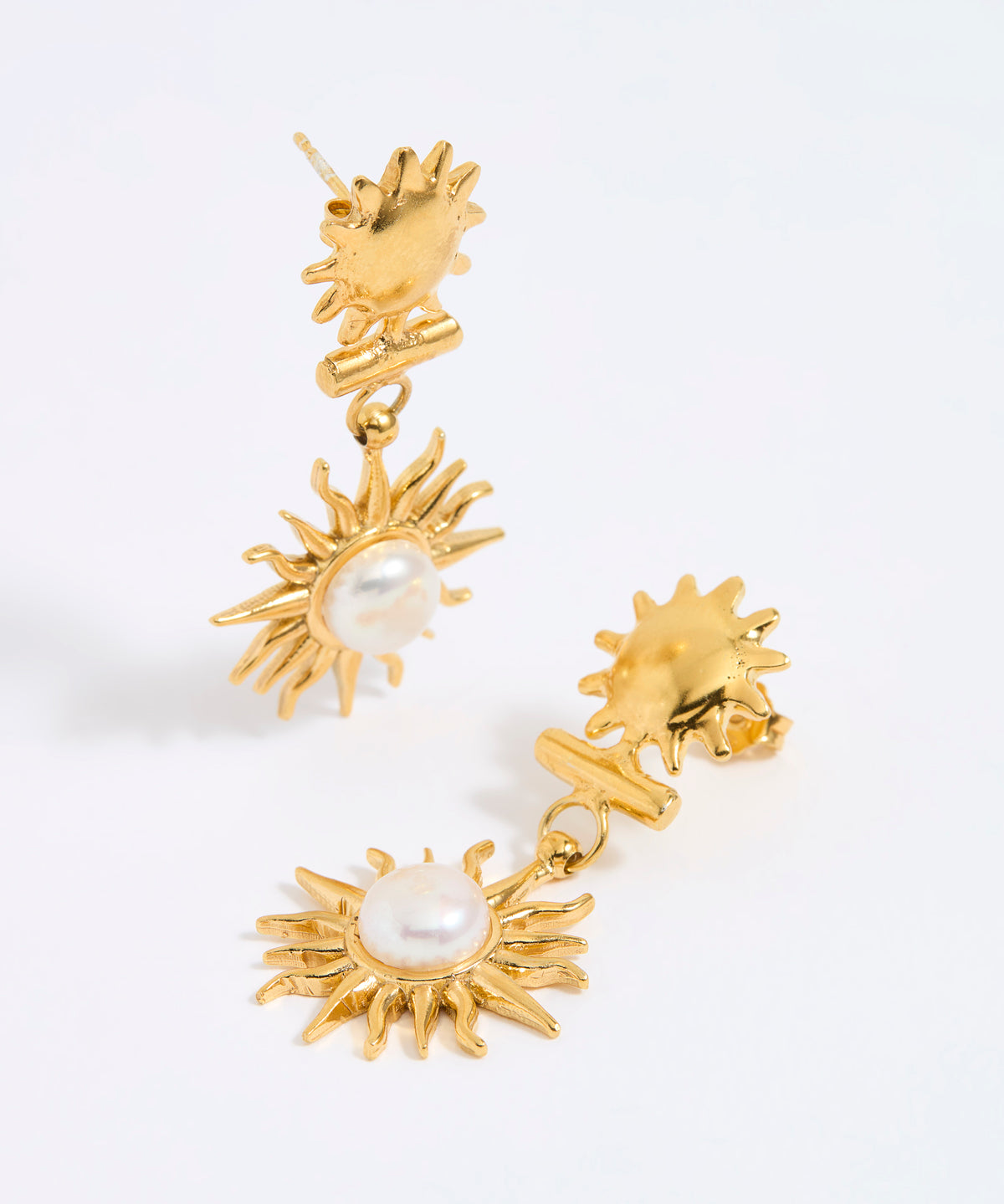 Gold sun-shaped earrings with pearl centers on a white background
