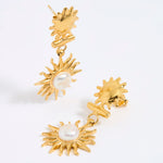 Gold sun-shaped earrings with pearl centers on a white background