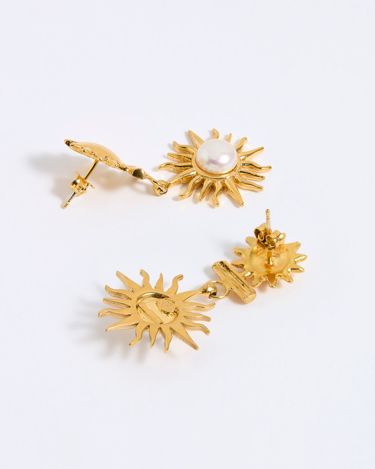 Gold sun-shaped earrings with a central pearl on a white background