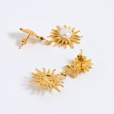 Gold sun-shaped earrings with a central pearl on a white background