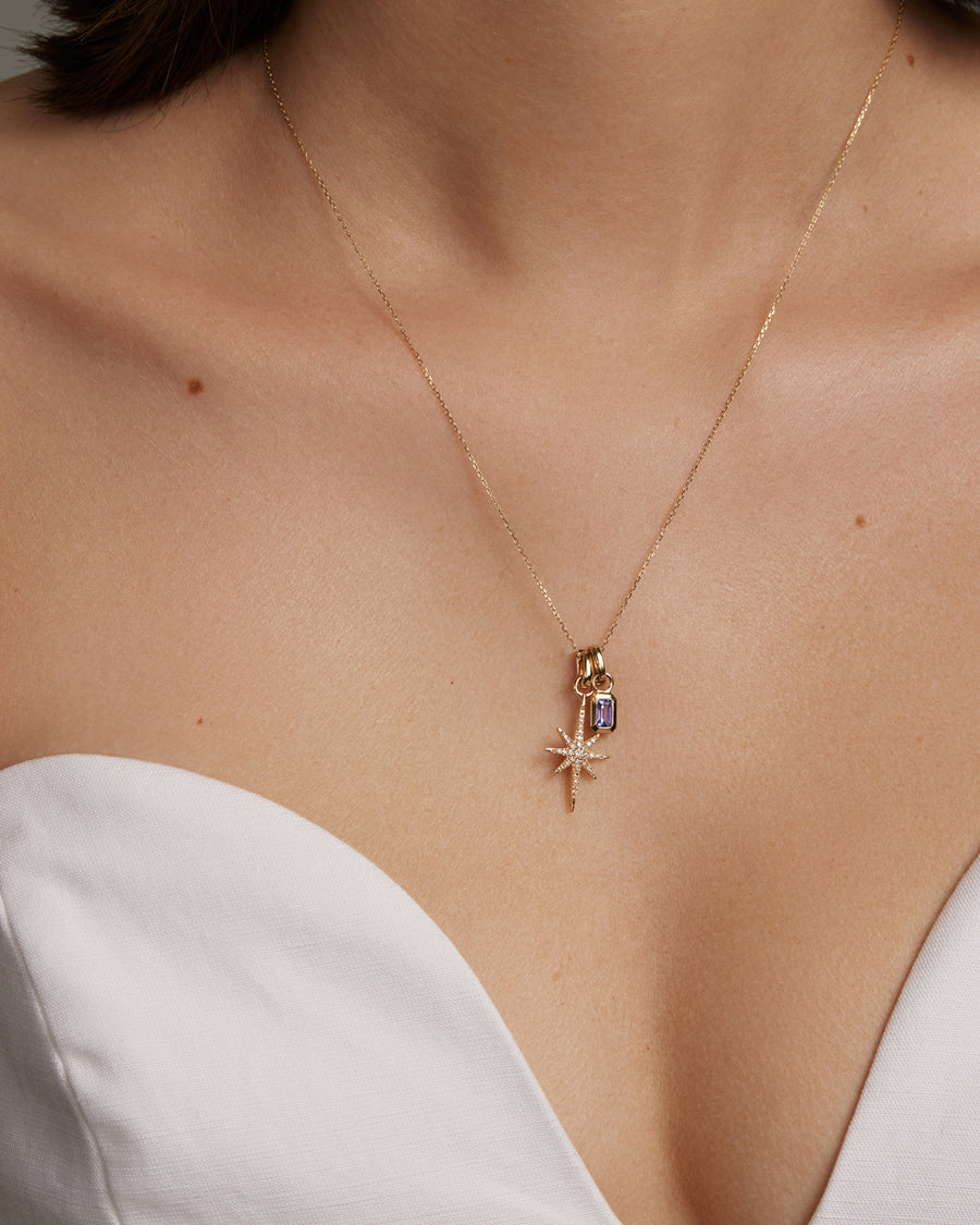 soru jewellery tanzanite birthstone charm and diamind star charm both hung from gold chain around models neck 