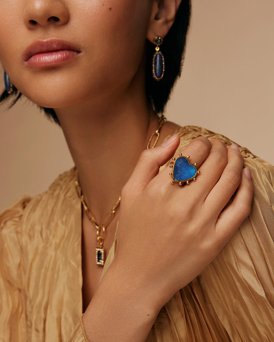 on model shot of blue tonal enamel in a heart shaped ring with gold beads on the outside