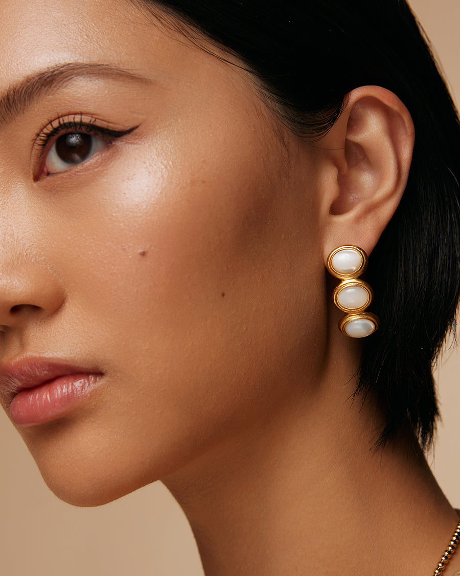 model shot of 3 stone pearl earrings set in yellow gold plated silver in a linear and curved shape