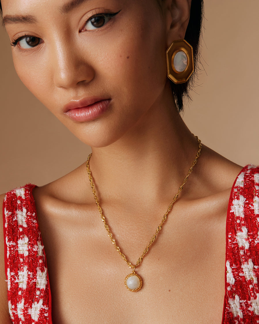 model shot of oversized octagonal stud earring with oval mother of pearl centre and moonstone necklace
