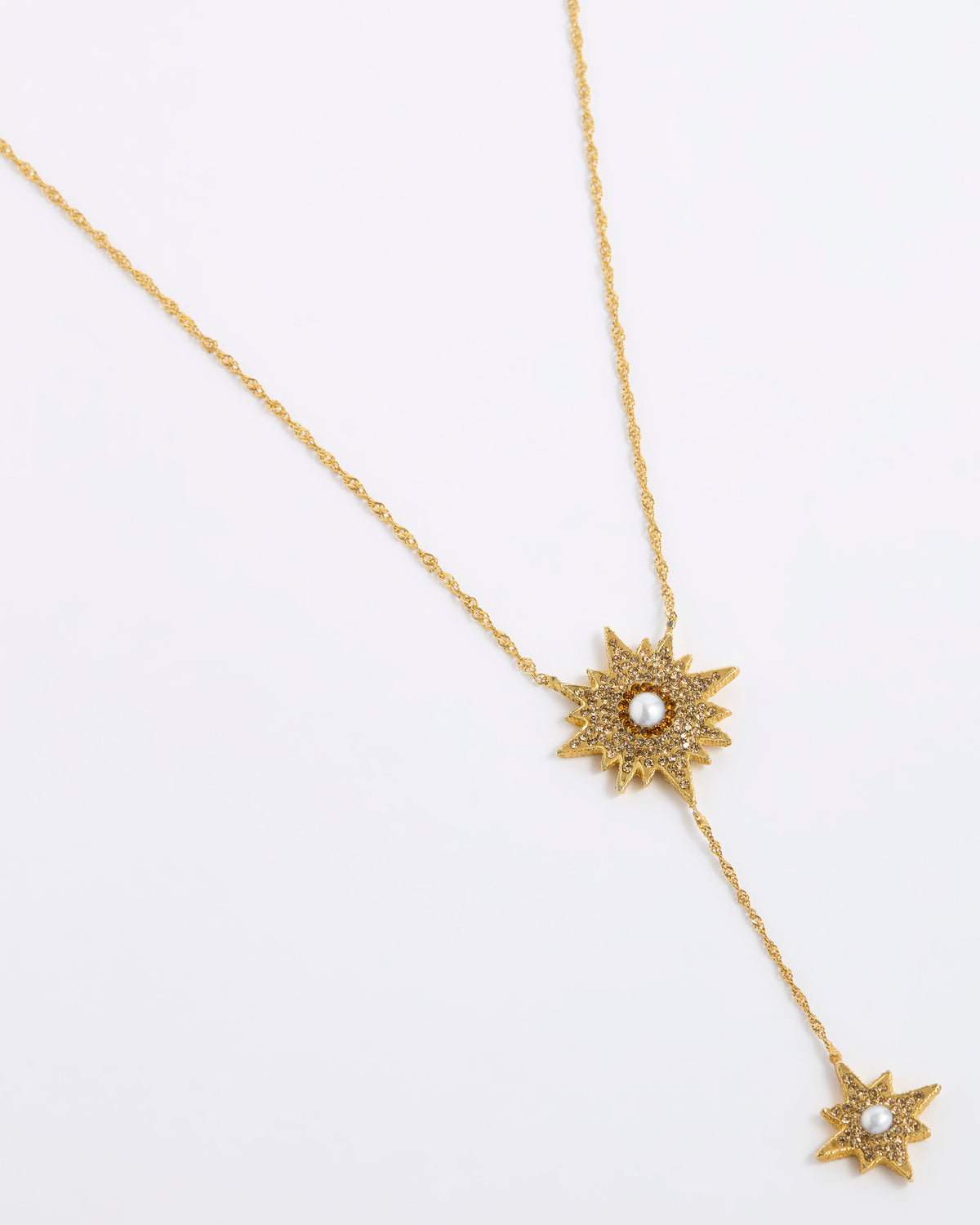 A gold-toned Y-necklace featuring two starburst sun motifs, each detailed with small clear stones and a central white pearl, displayed on a clean white background.