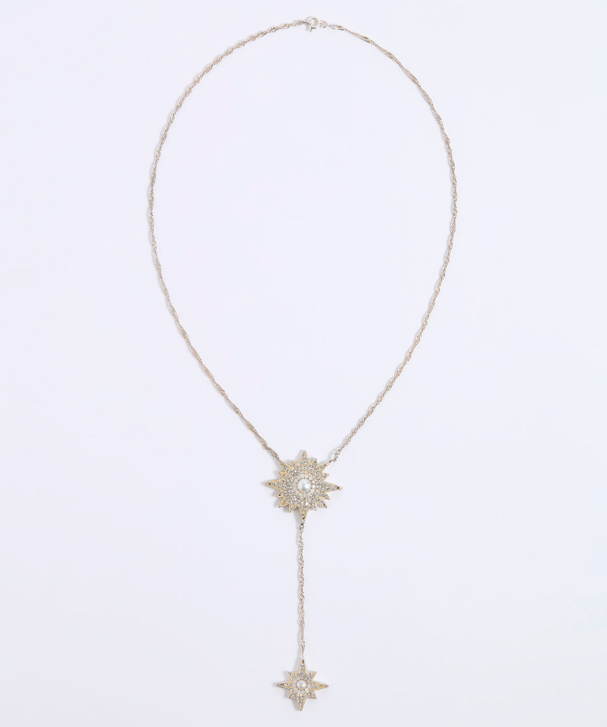 A delicate gold-toned Y-necklace featuring a central sunburst pendant with a clear central stone and a smaller matching sunburst pendant hanging from a drop chain, displayed on a clean white background.