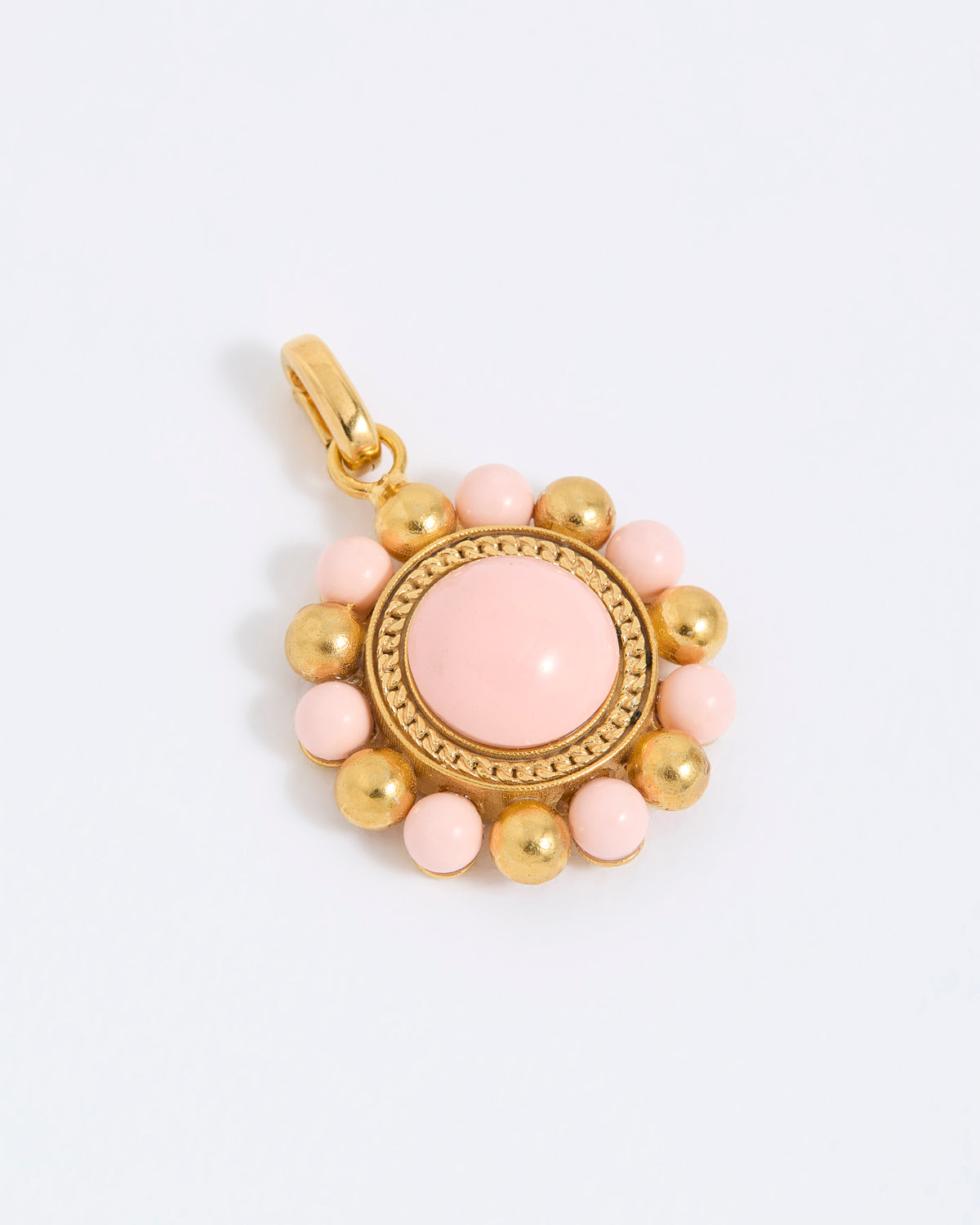 Gold coloured pendant with pink central stone and smaller pink stones on a white background