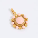 Gold coloured pendant with pink central stone and smaller pink stones on a white background